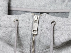 Detail view of gray fuzzy fleece hoodie featuring silver metal zipper and drawstring
