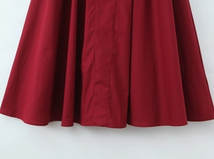 Détail de la robe bordeaux avec des plis structurés et une couture d'ourlet soignée