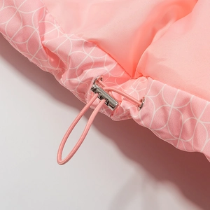 Détail de l'ourlet d'une veste en coton rose avec motif géométrique et cordon de serrage