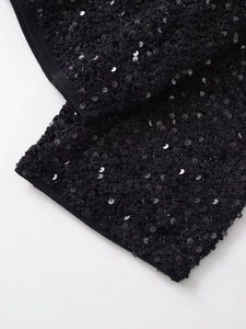 Close-up of black sequin embroidery on textured tweed fabric with ribbed edge detailing