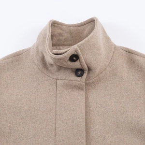 Detail of high stand collar and black button closure on oatmeal wool blend coat