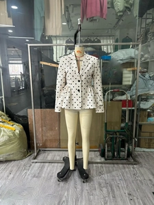 Detail of white blazer with black polka dots featuring a peplum hem and slim fit cut