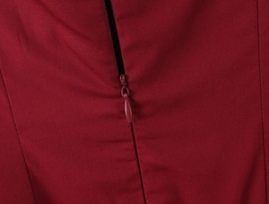 Détail de la fermeture éclair invisible sur une robe cintrée de couleur bordeaux