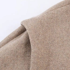Detailed macro shot of light brown wool blend fabric and shoulder seam craftsmanship
