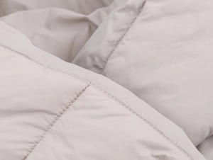 Close-up of beige quilted winter jacket fabric with high-quality water-repellent stitching