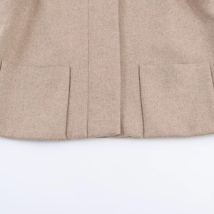 Detail of wool blend coat featuring symmetrical square pockets and soft beige texture