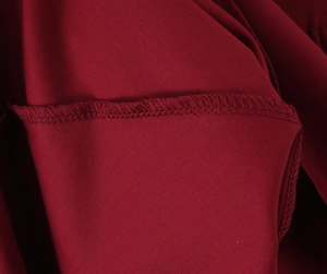 Vue macro de la couture surjet précise et de la texture fluide du tissu rouge foncé