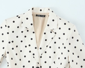 Detail of lapel collar and black polka dots on cream tailored blazer with neck brand label