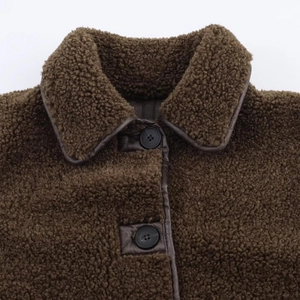Detail of brown teddy jacket showing faux shearling texture, leather trim, and buttons