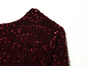 Close-up of wine red velvet fabric with shimmering sequins and shoulder stitching detail