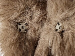 Detail of metal magnetic buckle closure on fluffy brown faux fur vest with soft texture