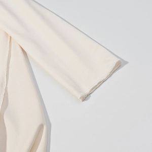 Détail de la manche d'une robe cape crème montrant la texture du sergé et les coutures