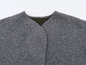 Close-up of grey textured wool fabric with clean round neckline and olive green lining