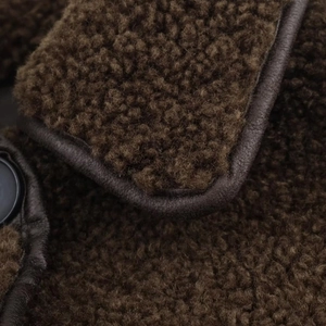 Detail of dark coffee shearling jacket showing plush texture and leather piping