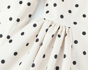 Close-up of ruched detail and polka dot pattern on women's long sleeve blazer jacket