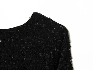 Close-up view of black sequin detailing on the collar and shoulder of the dress