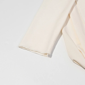 Gros plan sur la maille fine et les coutures de l'ourlet du tissu robe blanc crème