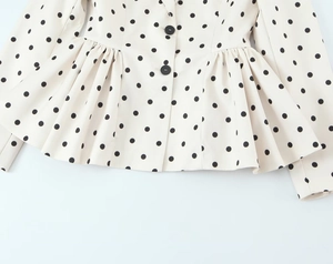 Detail of the peplum hem and black polka dot pattern on the white blazer jacket