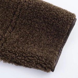 Detailed close-up of dark brown faux shearling fabric with premium leather binding edges