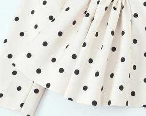 Detail shot of the polka dot blazer fabric showing material texture and pleat details