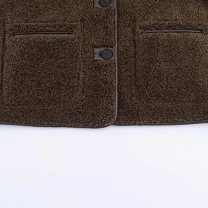 Detail of dark brown faux fur jacket with leather piping and symmetric patch pockets