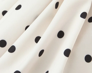 Close-up detail of the black polka dot pattern on premium white suit fabric material