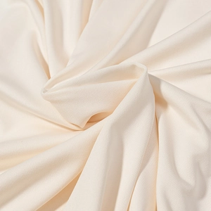Gros plan sur la texture du tissu côtelé beige doux montrant le drapé et les plis soyeux