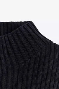 Détail du gilet en maille côtelée noire montrant le col montant et la texture du tissu