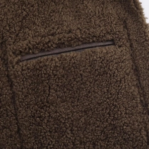 Close-up of brown faux shearling fabric with a horizontal welt pocket and soft texture