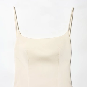 Detail of cream satin camisole top featuring ultra-thin straps and structured stitching