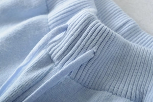 Detail of light blue knit pants showing ribbed waistband and matching drawstring