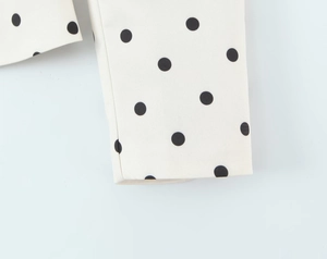 Detailed close-up of woven polka dot fabric showing stitching quality and print detail