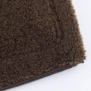 Macro detail of brown fleece fabric with coffee leather piping on the jacket edge