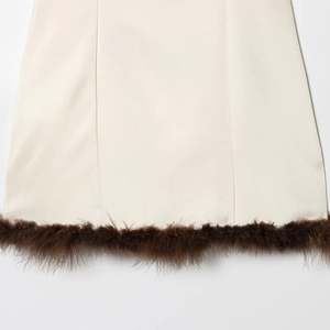 Close-up of ivory dress hem featuring premium textured fabric and dense brown feather trim