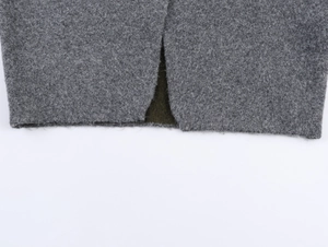 Detail of the slit on a gray wool sweater coat showing the smooth dark green inner lining
