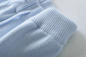 Macro view showing the ribbed cuffs and soft brushed texture of light blue knit trousers