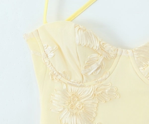 Détail de robe en maille jaune avec broderies florales 3D et corsage à lacets élégant