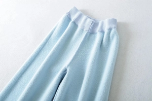 Detail of light blue knitted wide-leg trousers showing soft fleece texture and elastic waist