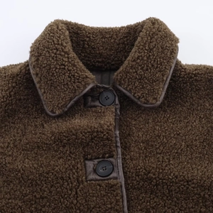 Front detail of dark brown shearling jacket with leather trim and round black buttons