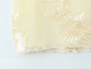 Gros plan sur tissu en maille jaune clair avec fleurs en ruban 3D et bords ondulés