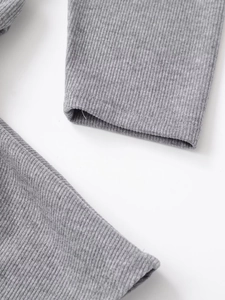 Close-up detail of grey ribbed knit fabric showing vertical texture and elastic cuffs