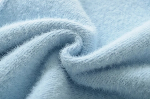 Close-up of soft light blue faux mink fur fabric texture with thick and fluffy plush fibers