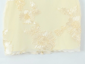 Détail de tulle crème avec une délicate broderie florale en satin sur l'ourlet