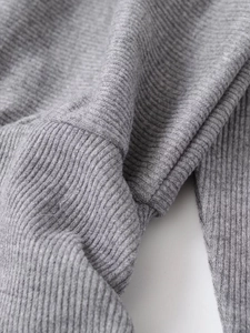 Detailed macro view of light gray ribbed knit fabric texture and seam craftsmanship
