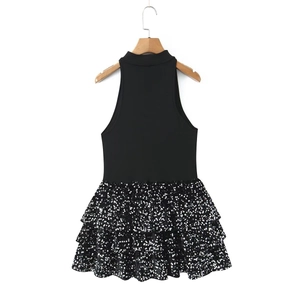 Détail de la jupe à sequins argentés et du haut en tricot noir à col montant
