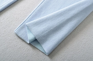 Close-up of light blue ribbed knit fabric with warm fleece lining for winter pants