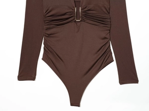 Detailed view of deep V-neckline with gold metal U-buckle and elegant ruched fabric