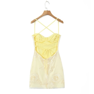 Détail du dos nu à lacets croisés et broderies florales sur cette robe courte jaune