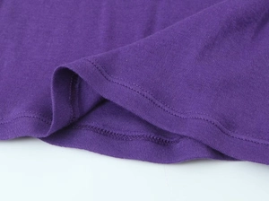 Detailed close-up of double-stitched hem on a purple long-sleeve knit top
