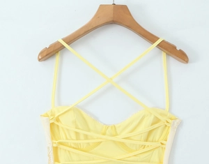 Détail de la robe jaune dos nu avec bretelles croisées multiples sur cintre en bois